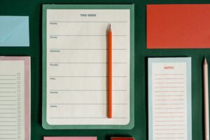 Flat lay of weekly planner, notes, envelopes, and pencils representing organization